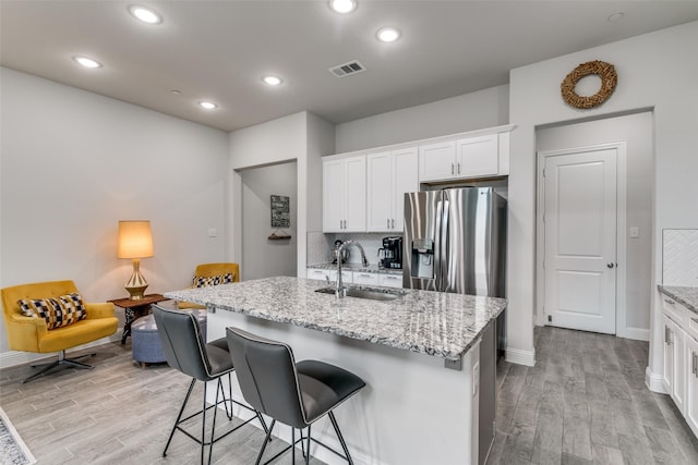 kitchen with stainless steel fridge with ice dispenser, light wood finished floors, a sink, and visible vents