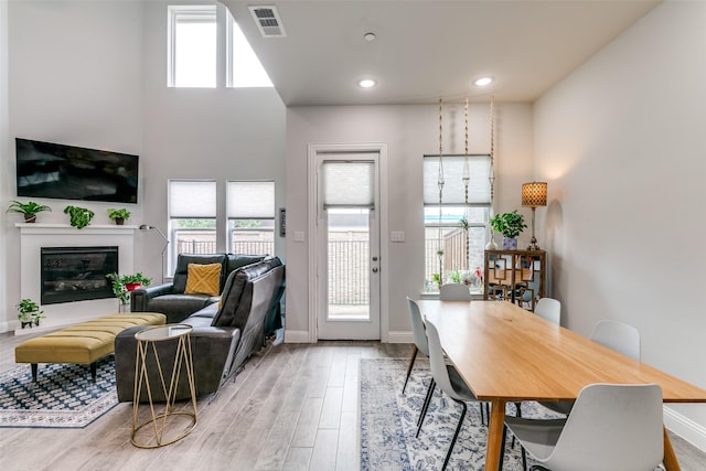 dining room with recessed lighting, visible vents, light wood-type flooring, baseboards, and a glass covered fireplace