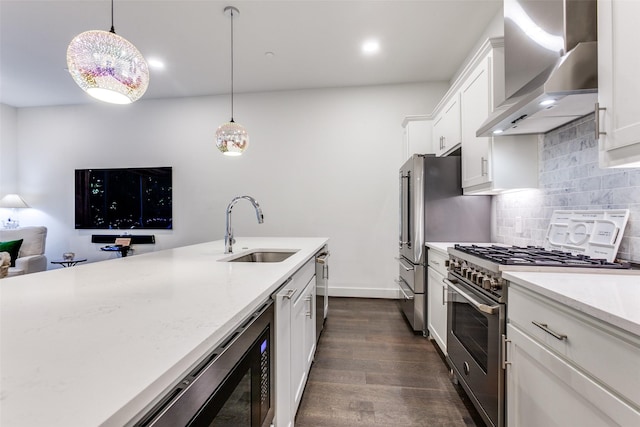 kitchen with a sink, dark wood finished floors, tasteful backsplash, wall chimney range hood, and appliances with stainless steel finishes