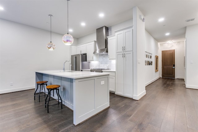 kitchen with high quality fridge, a breakfast bar, wall chimney range hood, visible vents, and decorative backsplash