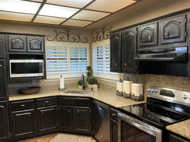 1302 Summit Dr, Mexia, TX 76667 - kitchen with light stone counters, a sink, dark cabinets, stainless steel appliances, and under cabinet range hood