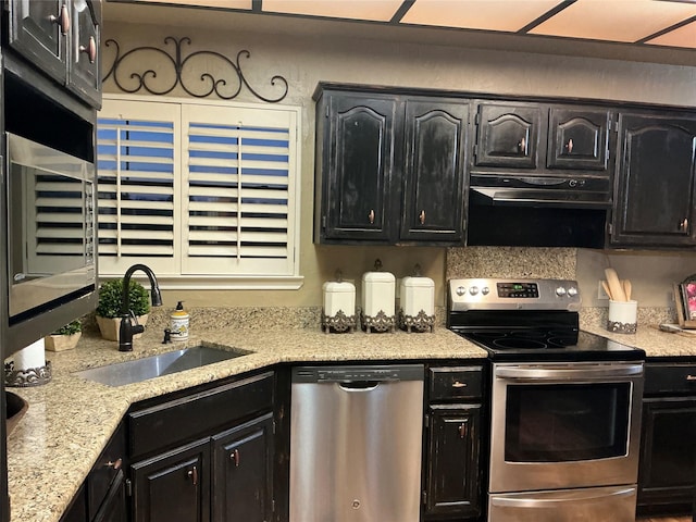 1302 Summit Dr, Mexia, TX 76667 - kitchen featuring stainless steel appliances, a sink, dark cabinetry, light stone countertops, and under cabinet range hood