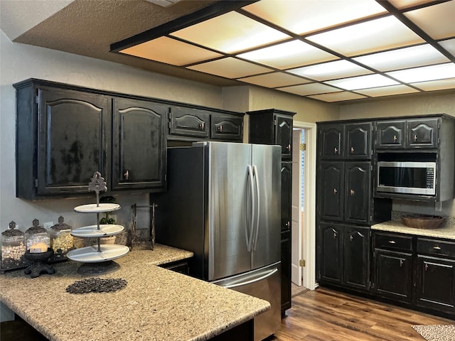 1302 Summit Dr, Mexia, TX 76667 - kitchen featuring stainless steel appliances, a peninsula, dark wood finished floors, dark cabinets, and light countertops