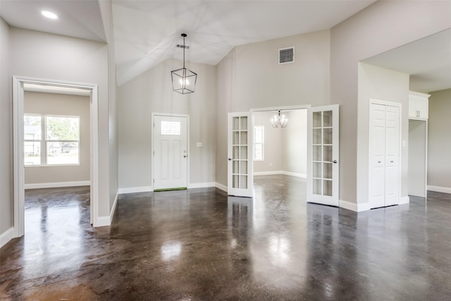 foyer with french doors, finished concrete floors, a healthy amount of sunlight, and high vaulted ceiling