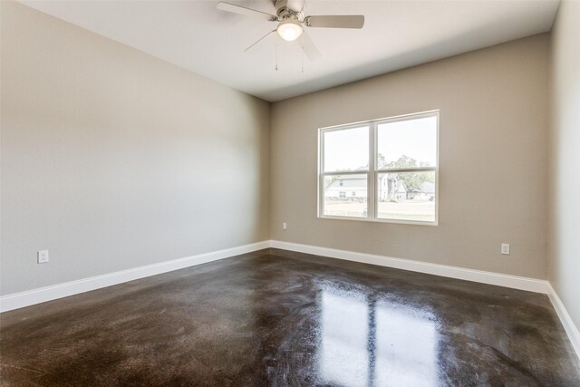 spare room featuring a ceiling fan, baseboards, and concrete floors
