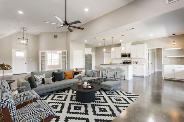 living area with visible vents, concrete flooring, baseboards, ceiling fan, and vaulted ceiling