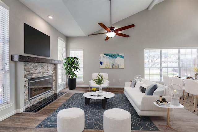 living area with baseboards, a fireplace, vaulted ceiling, and wood finished floors