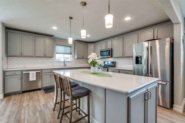1232 Bright Stars Dr, Little Elm, TX 76227 - kitchen featuring a sink, light wood-type flooring, decorative backsplash, gray cabinetry, and appliances with stainless steel finishes