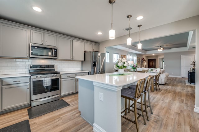 1232 Bright Stars Dr, Little Elm, TX 76227 - kitchen featuring appliances with stainless steel finishes, gray cabinetry, visible vents, open floor plan, and light wood-type flooring