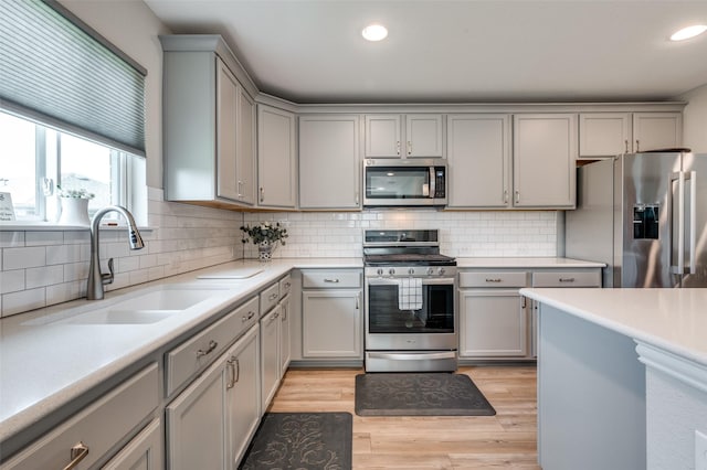 1232 Bright Stars Dr, Little Elm, TX 76227 - kitchen with stainless steel appliances, a sink, backsplash, light countertops, and gray cabinets