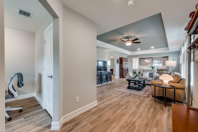 1232 Bright Stars Dr, Little Elm, TX 76227 - living room with a ceiling fan, light wood-style flooring, a tray ceiling, baseboards, and visible vents