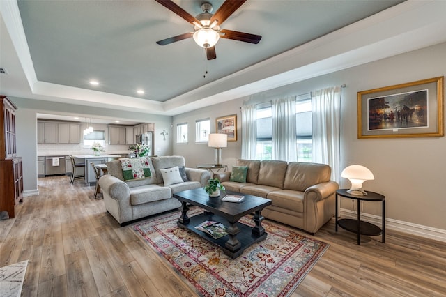 1232 Bright Stars Dr, Little Elm, TX 76227 - living room featuring a tray ceiling, baseboards, light wood-type flooring, and a ceiling fan