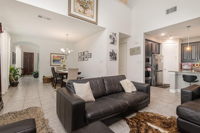living room featuring an inviting chandelier, arched walkways, light tile patterned flooring, and visible vents