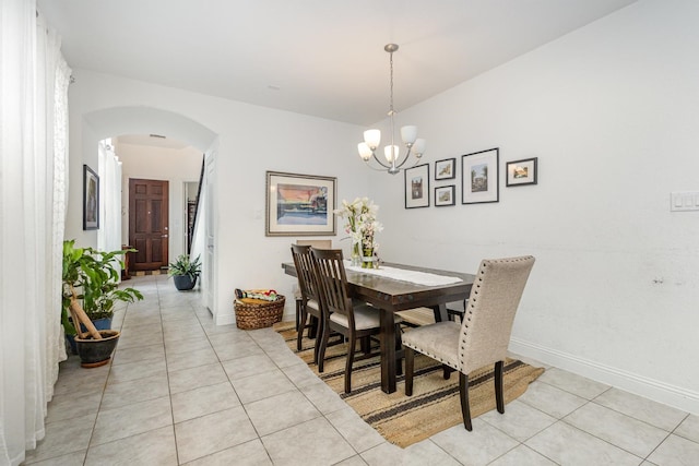 dining area featuring an inviting chandelier, arched walkways, baseboards, and light tile patterned floors