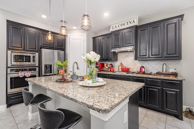 kitchen with appliances with stainless steel finishes, tasteful backsplash, light stone countertops, and visible vents