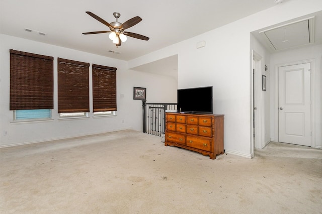 unfurnished living room with visible vents, attic access, carpet, and ceiling fan