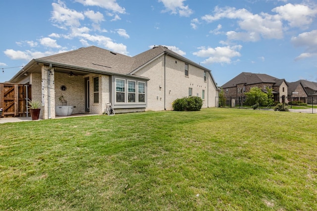 rear view of house with brick siding, a fenced backyard, and a patio area