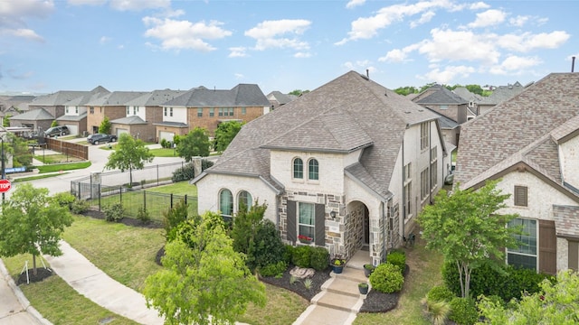 view of front of home featuring fence, a residential view, and roof with shingles