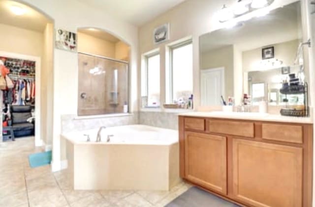 full bath featuring a spacious closet, a shower stall, tile patterned floors, a garden tub, and vanity