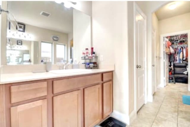 bathroom with tile patterned flooring, visible vents, vanity, and a spacious closet