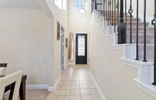 entrance foyer with light tile patterned floors, arched walkways, stairway, and baseboards