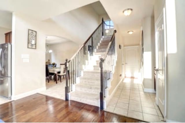 stairs featuring wood finished floors, baseboards, and arched walkways