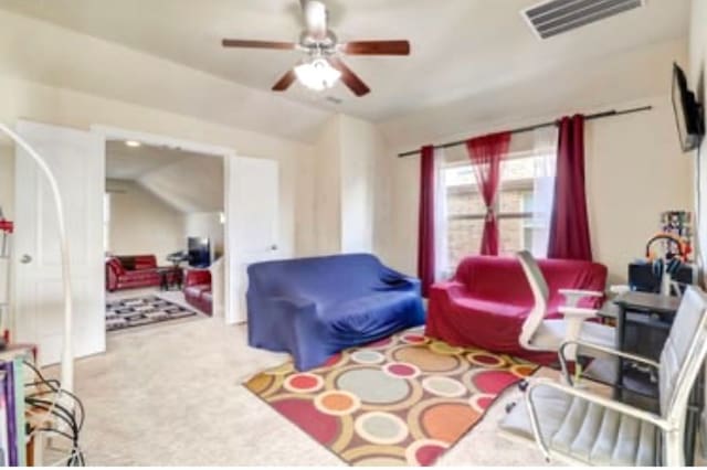 living area featuring visible vents, ceiling fan, carpet flooring, and vaulted ceiling