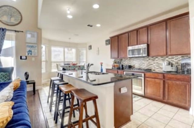 kitchen featuring a sink, appliances with stainless steel finishes, dark countertops, recessed lighting, and backsplash