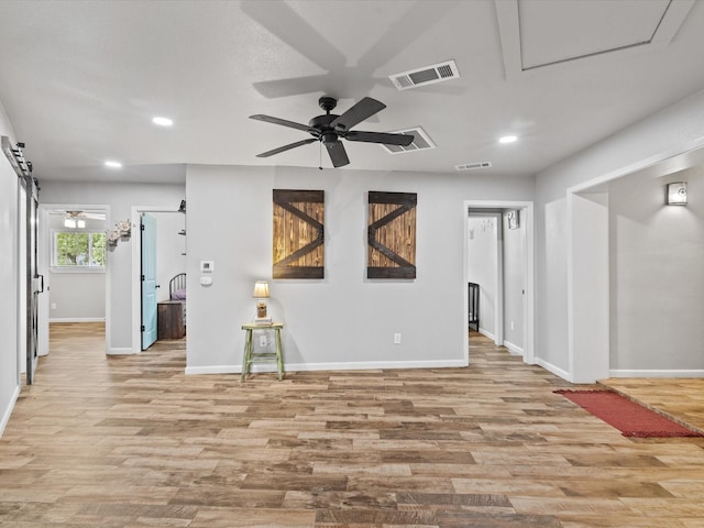 interior space with baseboards, ceiling fan, light wood-style flooring, and visible vents