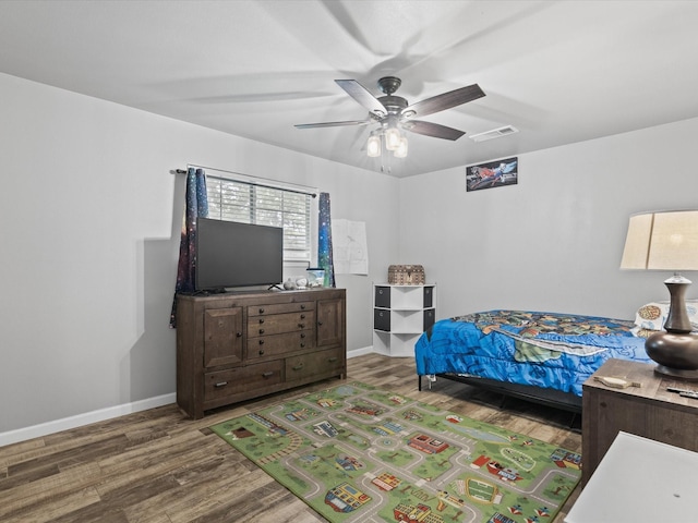 bedroom with baseboards, wood finished floors, and visible vents