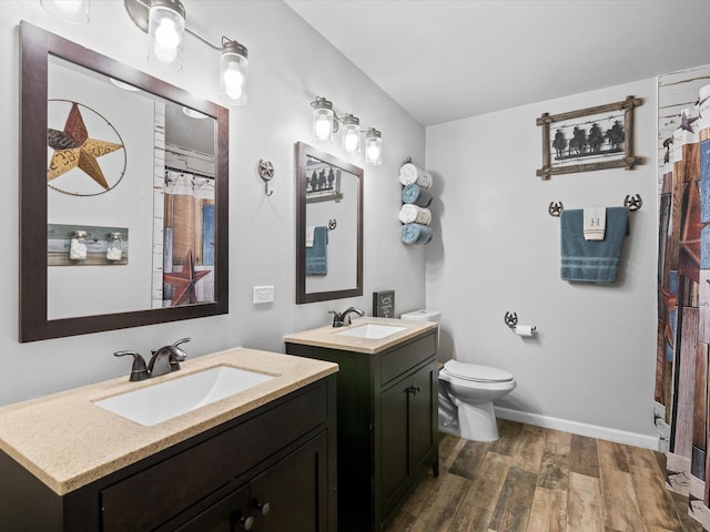 full bathroom featuring a sink, wood finished floors, toilet, and two vanities