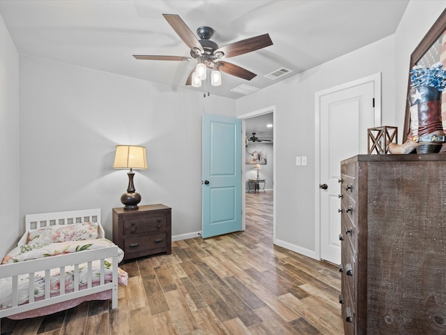 bedroom with baseboards, ceiling fan, wood finished floors, and visible vents