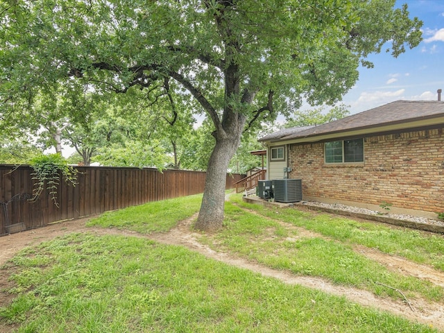 view of yard with central AC and a fenced backyard