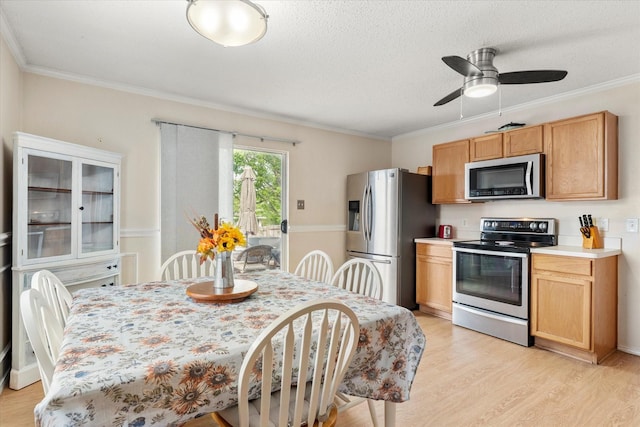 kitchen featuring crown molding, appliances with stainless steel finishes, light wood-style floors, and light countertops