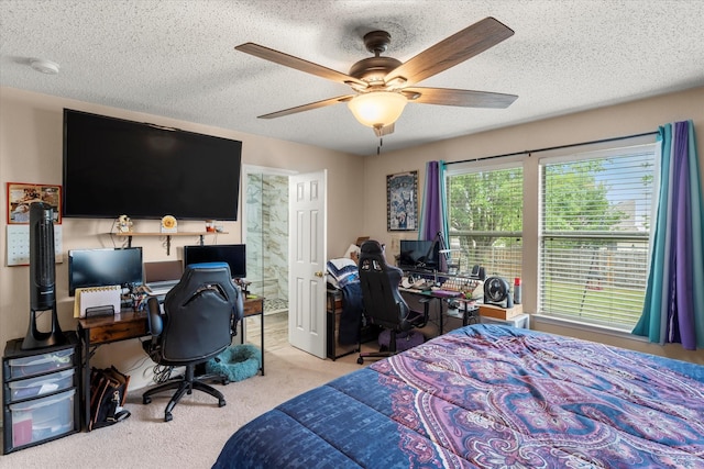 bedroom with a ceiling fan, ensuite bath, carpet, and a textured ceiling