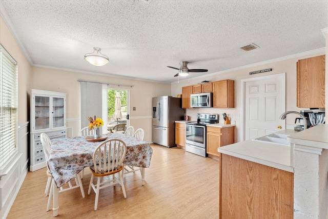 kitchen with visible vents, ornamental molding, a sink, a textured ceiling, and appliances with stainless steel finishes