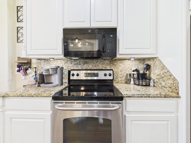 118 Chickadee Dr, Whitehouse, TX 75791 - kitchen featuring decorative backsplash, black microwave, stainless steel range with electric stovetop, and white cabinetry