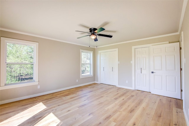 unfurnished bedroom featuring baseboards, multiple windows, multiple closets, and light wood-style floors