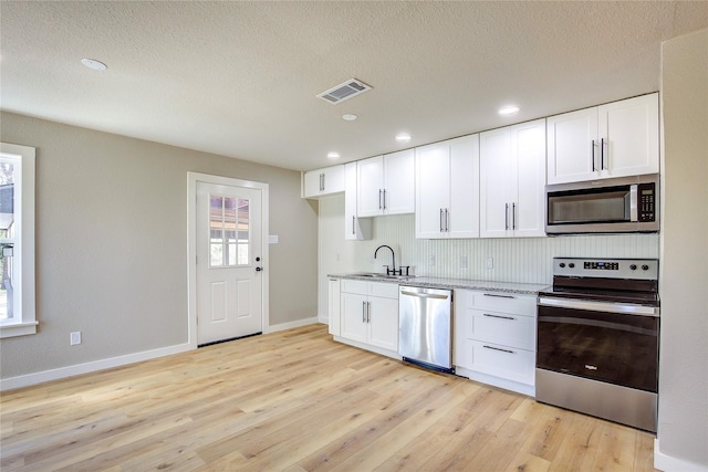 kitchen with light stone countertops, stainless steel appliances, baseboards, and visible vents