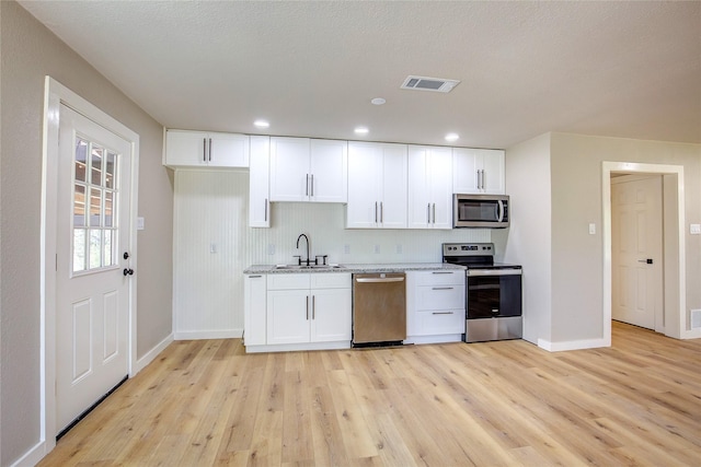 kitchen featuring a sink, light wood-style flooring, baseboards, appliances with stainless steel finishes, and visible vents