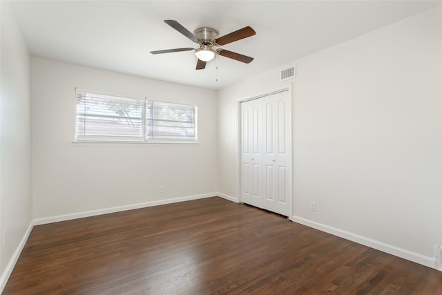 unfurnished bedroom with visible vents, a closet, baseboards, dark wood-style floors, and a ceiling fan