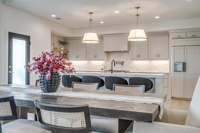 kitchen with light countertops, tasteful backsplash, an island with sink, and a sink