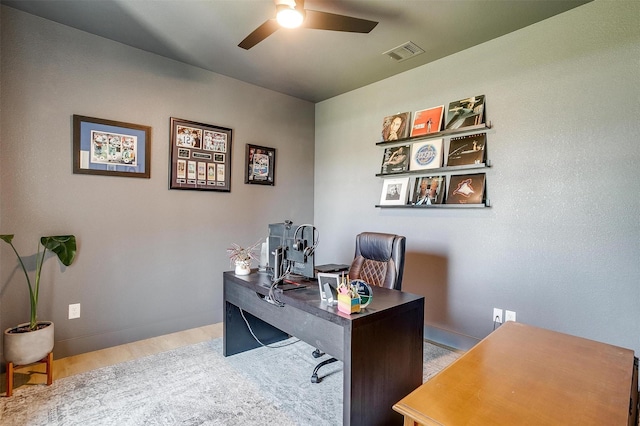 office area with wood finished floors, visible vents, a ceiling fan, and baseboards