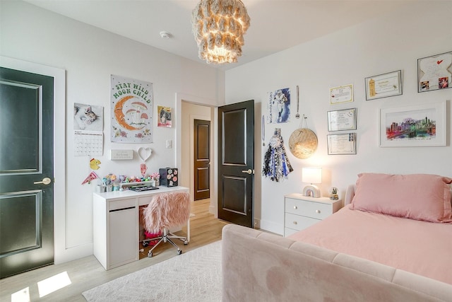 bedroom with light wood-style flooring and an inviting chandelier