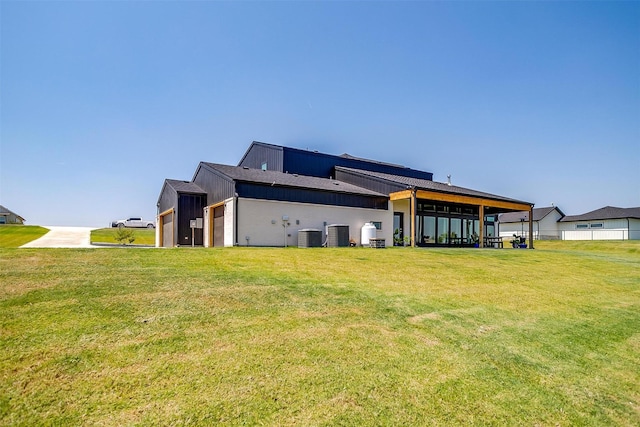 rear view of house featuring a lawn, cooling unit, and a garage