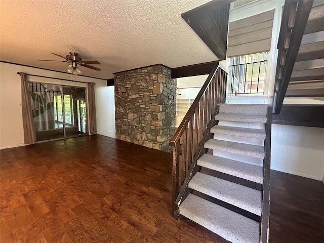 staircase with wood finished floors, a textured ceiling, and a ceiling fan