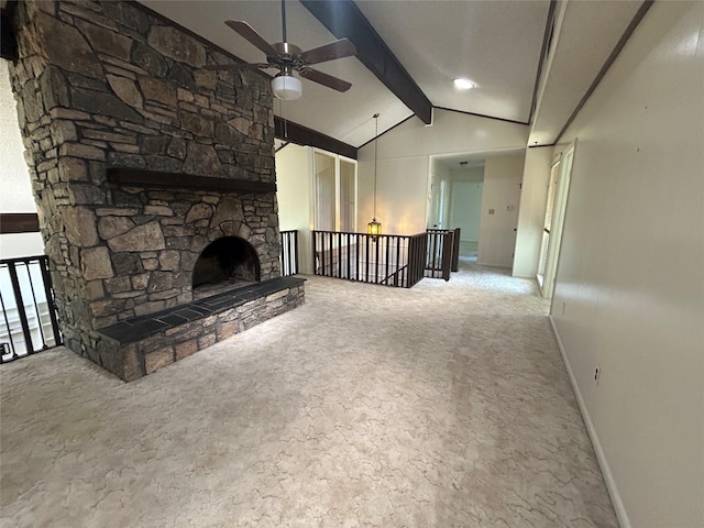 unfurnished living room with a ceiling fan, a stone fireplace, vaulted ceiling with beams, carpet, and baseboards
