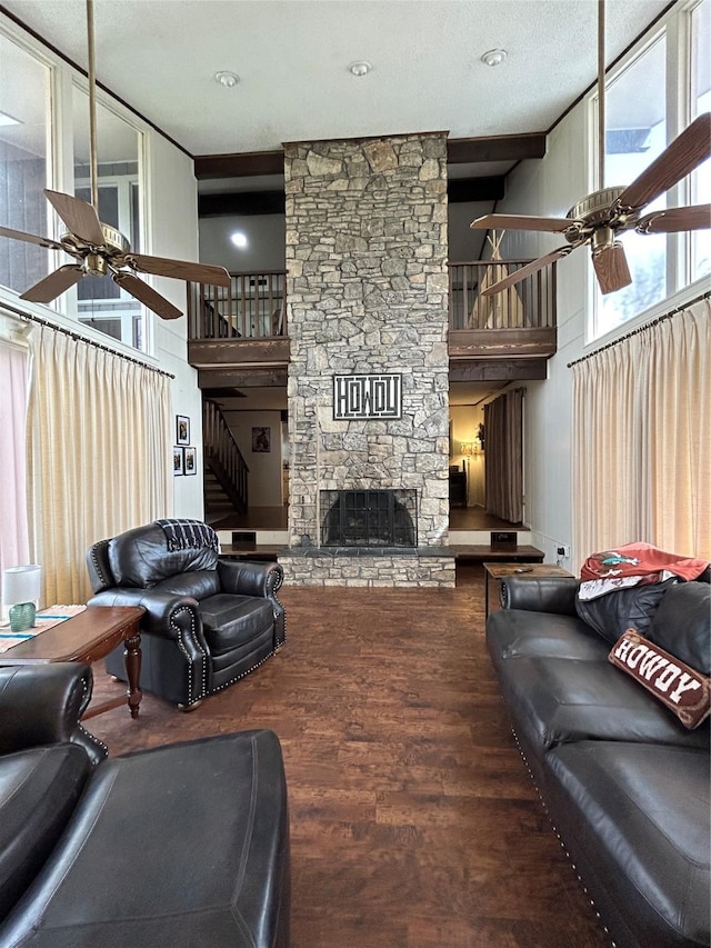 living room with stairway, a stone fireplace, wood finished floors, ceiling fan, and a towering ceiling