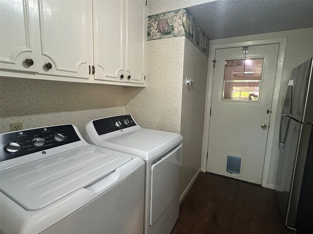 laundry area featuring washing machine and dryer, baseboards, cabinet space, and wallpapered walls
