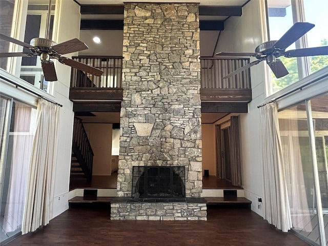 unfurnished living room featuring a fireplace, stairway, wood finished floors, and ceiling fan